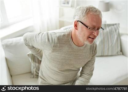 people, healthcare and problem concept - unhappy senior man suffering from pain in back or reins at home