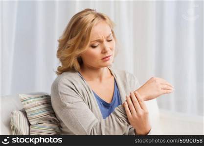 people, healthcare and problem concept - unhappy woman suffering from pain in hand at home