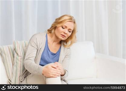 people, healthcare and problem concept - unhappy woman suffering from pain in leg at home