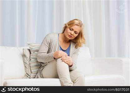 people, healthcare and problem concept - unhappy woman suffering from pain in leg at home
