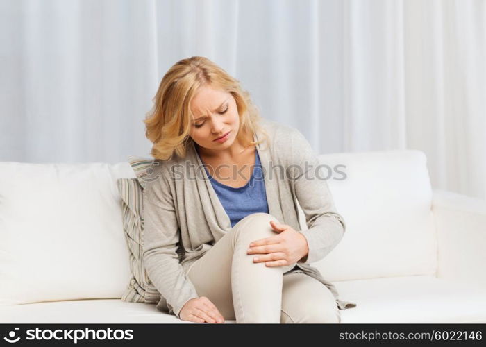 people, healthcare and problem concept - unhappy woman suffering from pain in leg at home