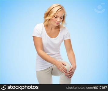 people, healthcare and problem concept - unhappy woman suffering from pain in leg over blue background