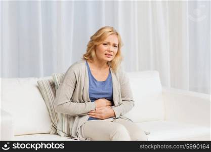 people, healthcare and problem concept - unhappy woman suffering from stomach ache at home