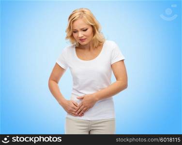 people, healthcare and problem concept - unhappy woman suffering from stomach ache over blue background