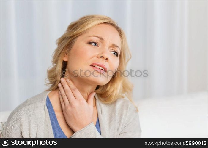 people, healthcare and problem concept - unhappy woman touching her neck and suffering from throat pain at home