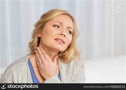 people, healthcare and problem concept - unhappy woman touching her neck and suffering from throat pain at home