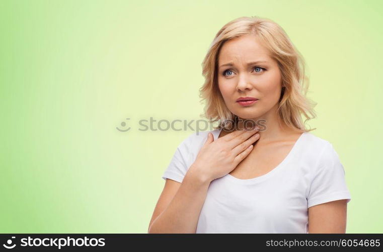 people, healthcare and problem concept - unhappy woman touching her neck and suffering from throat pain over green natural background