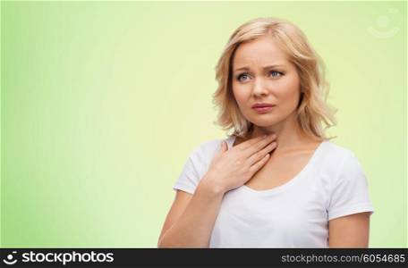 people, healthcare and problem concept - unhappy woman touching her neck and suffering from throat pain over green natural background