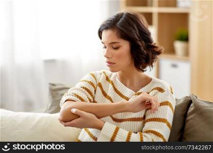 people, healthcare and problem concept - unhappy young woman suffering from pain in hand at home. unhappy woman suffering from pain in hand at home