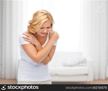 people, healthcare and social issue concept - unhappy woman suffering from pain or violence over living room background