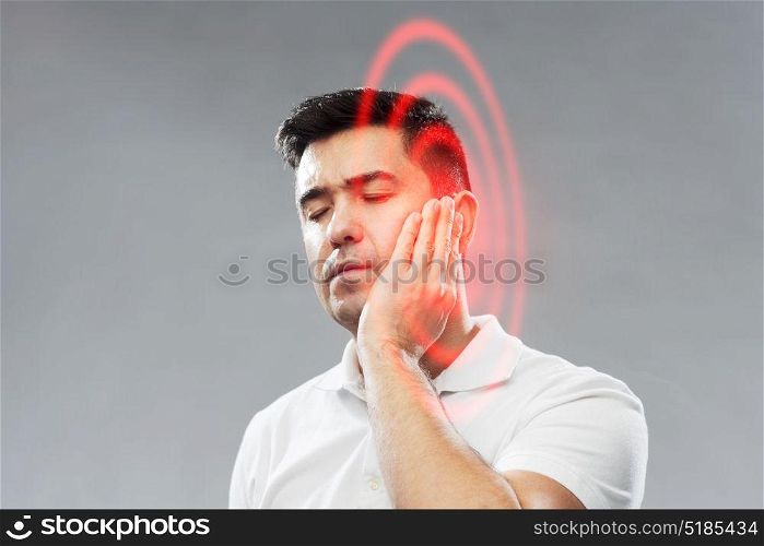 people, healthcare, dentistry and problem concept - unhappy man suffering toothache over gray background. unhappy man suffering toothache