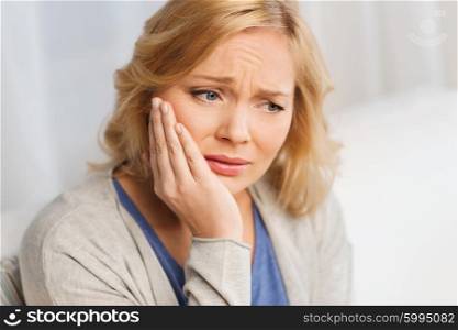 people, healthcare, dentistry and problem concept - unhappy woman suffering toothache at home