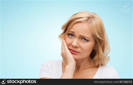 people, healthcare, dentistry and problem concept - unhappy woman suffering toothache over blue background