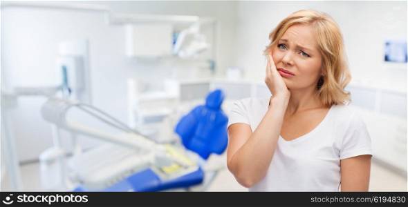 people, healthcare, dentistry and problem concept - unhappy woman suffering toothache over dental office background