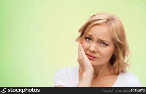 people, healthcare, dentistry and problem concept - unhappy woman suffering toothache over green natural background
