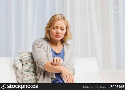 people, healthcare, dermatology, allergy and health problem concept - unhappy woman suffering from hand inch at home