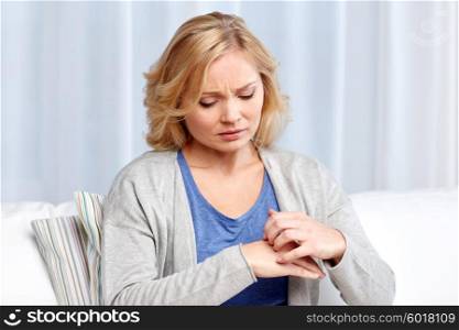 people, healthcare, dermatology, allergy and health problem concept - unhappy woman suffering from hand inch at home