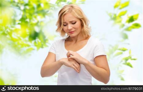 people, healthcare, dermatology, allergy and health problem concept - unhappy woman suffering from hand inch over green natural background