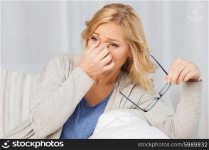 people, healthcare, eyesight, stress and problem concept - tired woman taking eyeglasses off at home