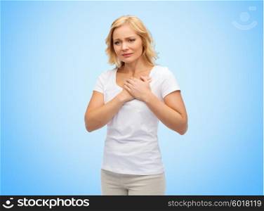 people, healthcare, heart disease and problem concept - unhappy woman suffering from heartache over blue background