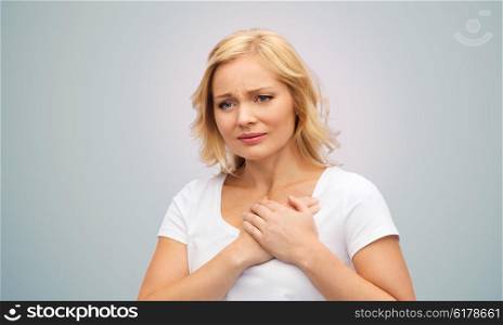 people, healthcare, heart disease and problem concept - unhappy woman suffering from heartache over gray background