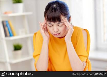 people, healthcare, stress and problem concept - unhappy asian young woman suffering from headache at home