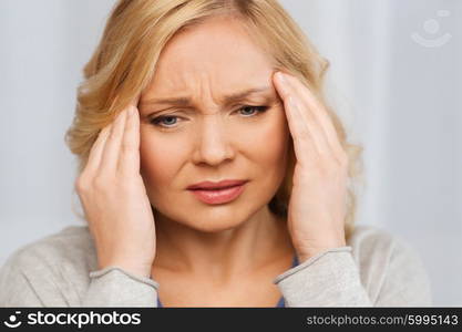 people, healthcare, stress and problem concept - unhappy woman suffering from headache at home