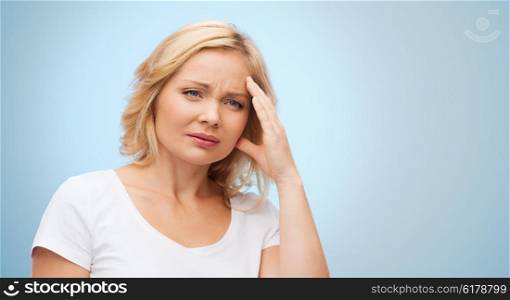 people, healthcare, stress and problem concept - unhappy woman suffering from headache over blue background