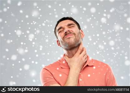 people, healthcare, winter, christmas and problem concept - unhappy man touching his neck and suffering from throat pain over snow on gray background