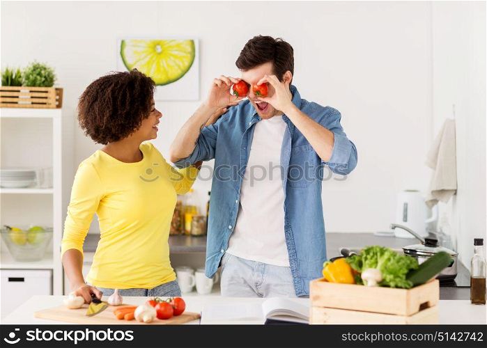 people, healthy eating and international concept - happy couple cooking food and having fun at home kitchen. happy couple cooking food and having fun at home