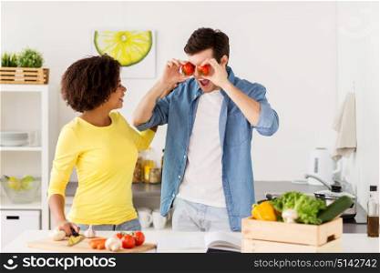people, healthy eating and international concept - happy couple cooking food and having fun at home kitchen. happy couple cooking food and having fun at home
