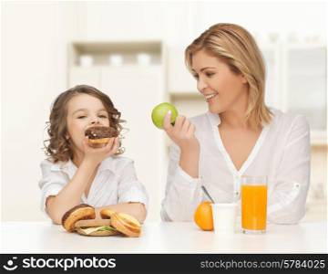 people, healthy lifestyle, family and food concept - happy mother and daughter eating healthy breakfast over home kitchen background