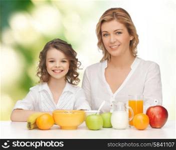 people, healthy lifestyle, family and food concept - happy mother and daughter eating healthy breakfast over green background