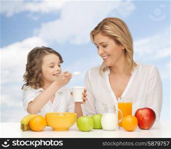 people, healthy lifestyle, family and food concept - happy mother and daughter eating healthy breakfast over blue sky background