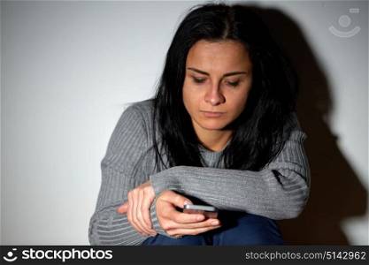 people, helpline and domestic violence concept - unhappy crying woman with smartphone messaging or dialing number. unhappy crying woman with smartphone