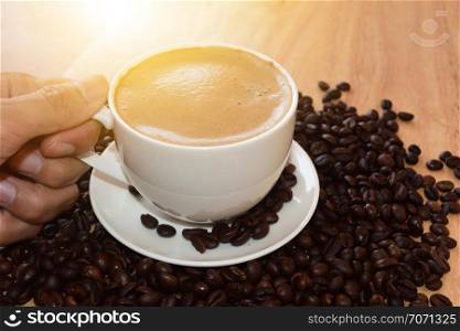 People holding coffee mugs drinking coffee on the table and coffee beans