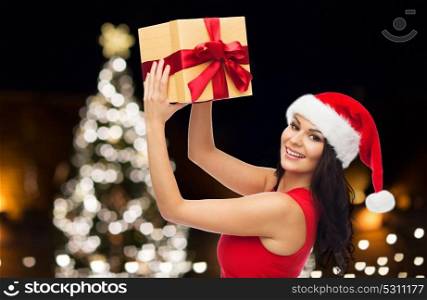 people, holidays and celebration concept - beautiful sexy woman in red dress with gift box over christmas tree background. beautiful woman in red dress with christmas gift