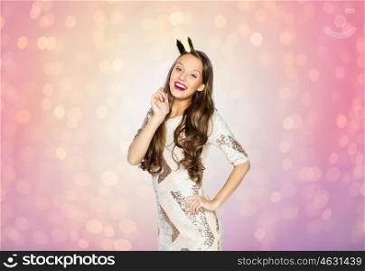people, holidays and celebration concept - happy young woman or teen girl in party dress and princess crown over rose quartz and serenity lights background