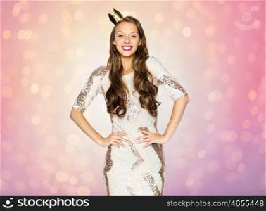 people, holidays and celebration concept - happy young woman or teen girl in party dress and princess golden crown over rose quartz and serenity lights background