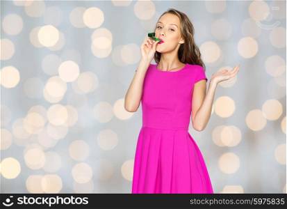 people, holidays and celebration concept - happy young woman or teen girl in pink dress and party cap over lights background
