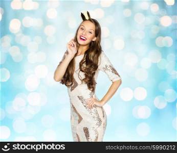 people, holidays and celebration concept - happy young woman or teen girl in party dress and princess crown over blue lights background