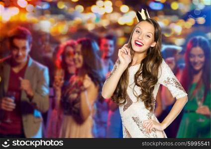 people, holidays and celebration concept - happy young woman or teen girl in party dress and princess crown over night club disco lights background