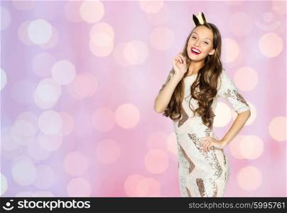 people, holidays and celebration concept - happy young woman or teen girl in party dress and princess crown over pink lights background