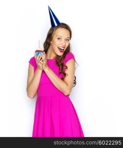 people, holidays and celebration concept - happy young woman or teen girl in pink dress and party cap with birthday cupcake