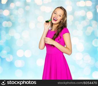 people, holidays and celebration concept - happy young woman or teen girl in pink dress and party cap over blue holidays lights background
