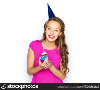 people, holidays and celebration concept - happy young woman or teen girl in pink dress and party cap with birthday cupcake