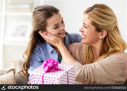 people, holidays and family concept - happy girl giving birthday present to mother at home. girl giving birthday present to mother at home. girl giving birthday present to mother at home
