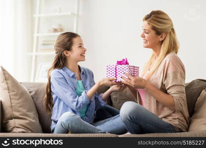 people, holidays and family concept - happy girl giving birthday present to mother at home. girl giving birthday present to mother at home