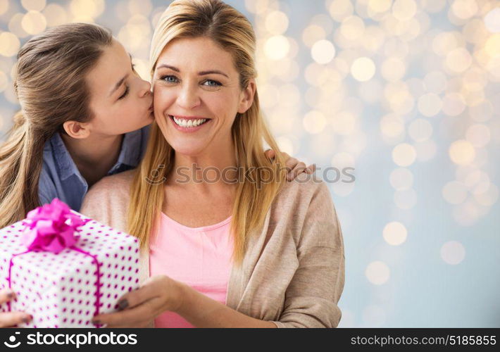 people, holidays and family concept - happy girl giving birthday present to mother over lights background. girl giving birthday present to mother over lights