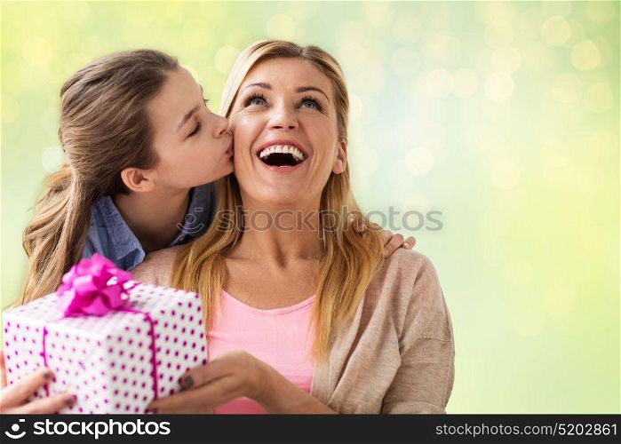 people, holidays and family concept - happy girl giving birthday present to mother over lights background. girl giving birthday present to mother over lights